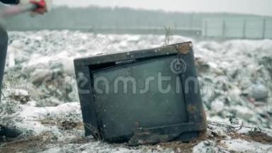 一个人用锤子破坏旧电视。 一个拿着锤子的人打碎了电视屏幕。